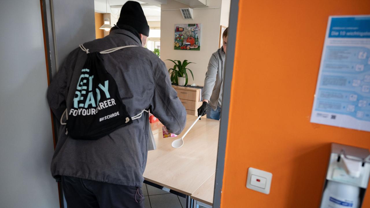 Ein junger Mann arbeitet als Freiwilliger in der Obdachlosentagesstätte Olga 46.Er reicht einem Mann ein Getränk und etwas zu essen. Das Foto ist von 2020.