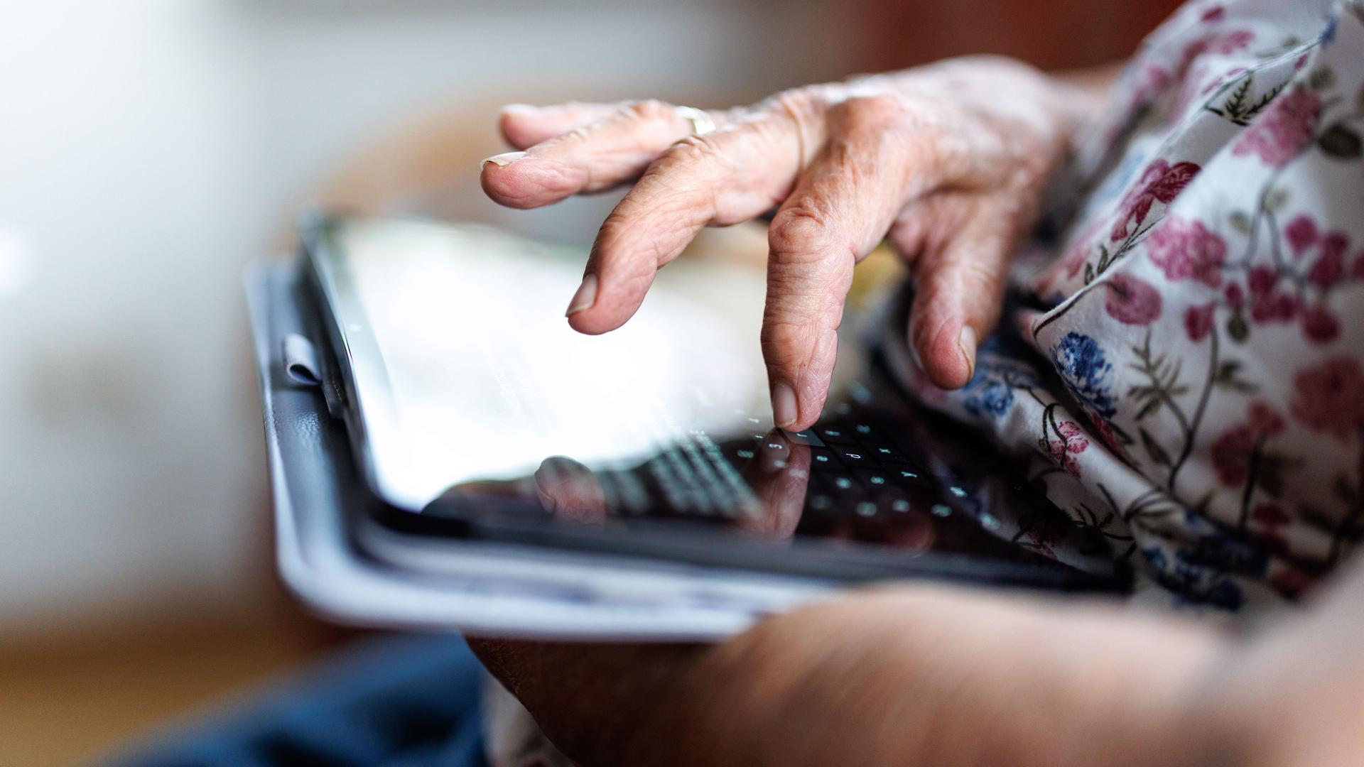 Eine 95-jährige Dame bedient ihr Tablet und schreibt eine Nachricht in einem Messenger.