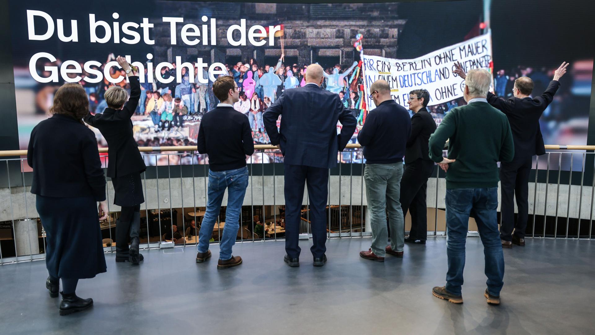 Der neue Slogan „Du bist Teil der Geschichte“ ist im Haus der Geschichte auf einer Videowand zu sehen, davor stehen Menschen. Das Haus der Geschichte in Bonn eröffnet seine neu gestaltete Dauerausstellung.