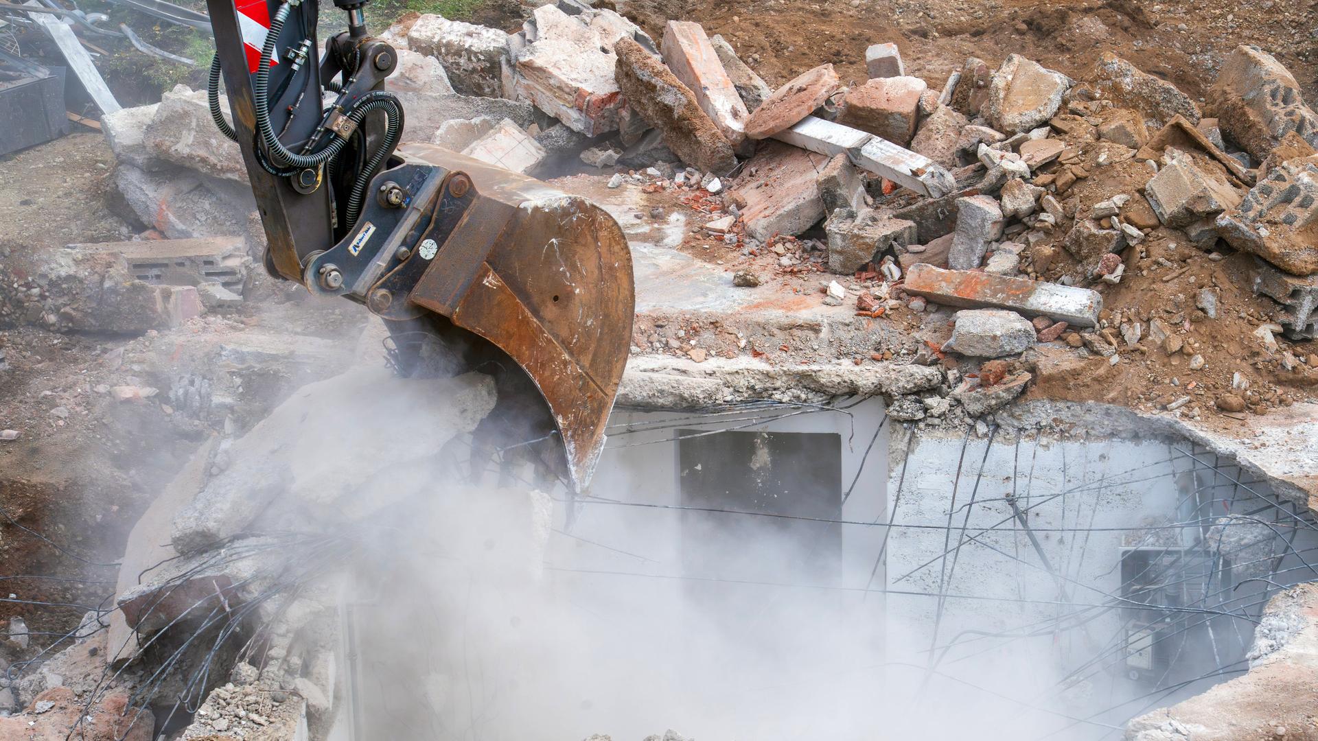 Abbruch eines alten Einfamilienhauses, Bagger hebt Fundament und Keller aus