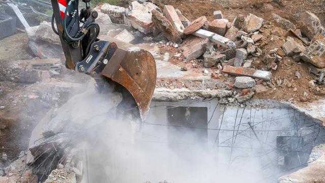 Abbruch eines alten Einfamilienhauses, Bagger hebt Fundament und Keller aus