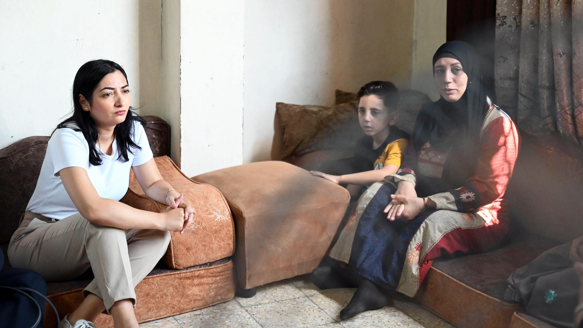 Reem Alabali Radovan (SPD, l), Bundesministerin für Wirtschaftliche Zusammenarbeit und Entwicklung, sitzt im UNRWA-Marka-Camp auf einer Matratze auf dem Boden neben zwei Geflüchteten aus Gaza