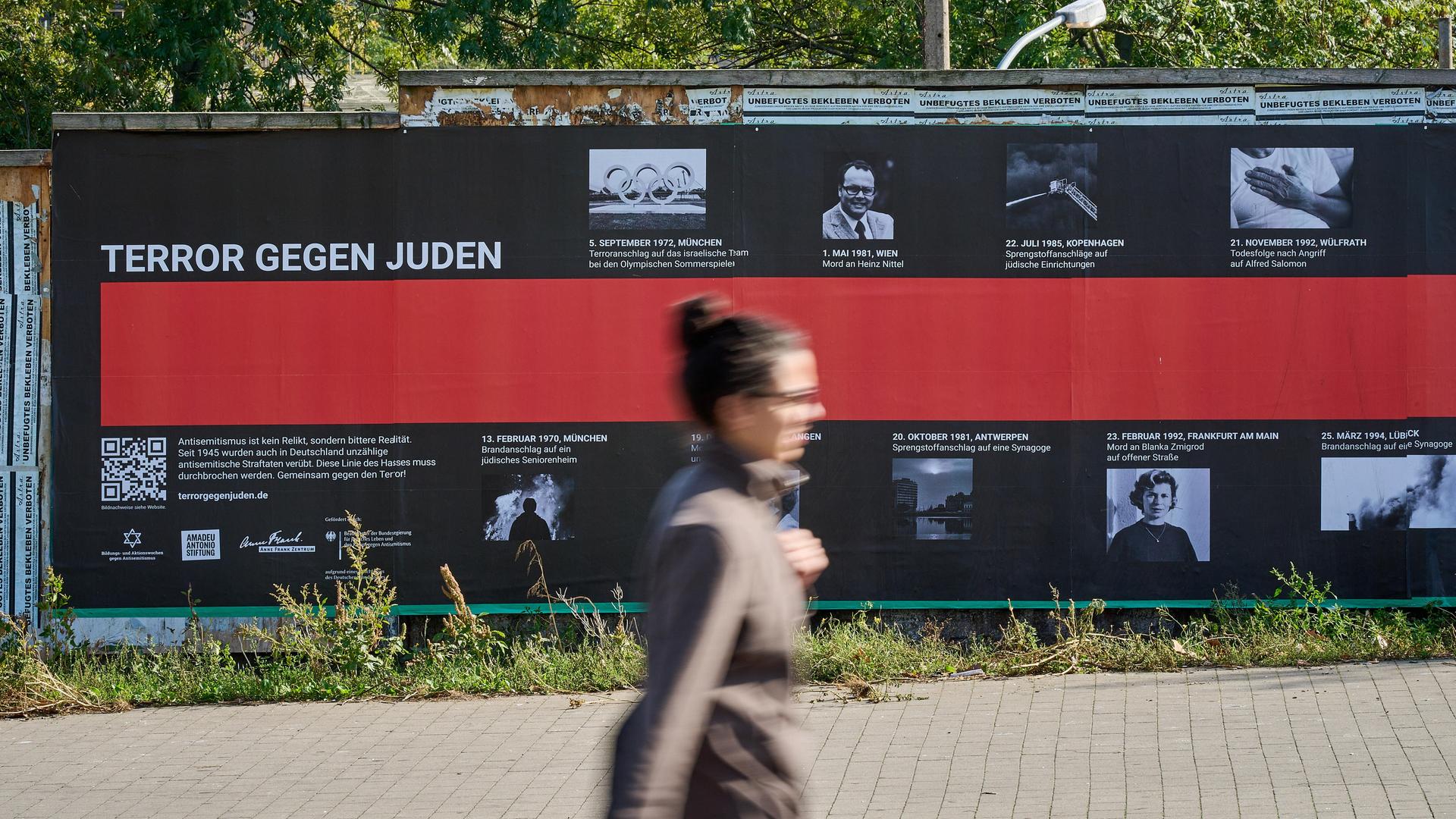 Eine Frau geht an einem Plakat mit der Aufschrift "Terror gegen Juden" vorbei.