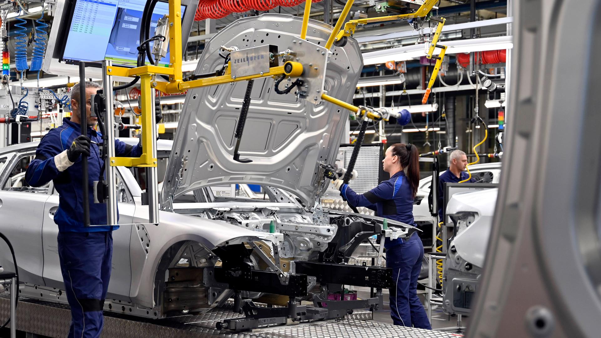 Autos und BMW-Mitarbeiter in der Fertigung beim Werksrundgang von Bundeskanzler Olaf Scholz (SPD) im BMW Group Werk München.