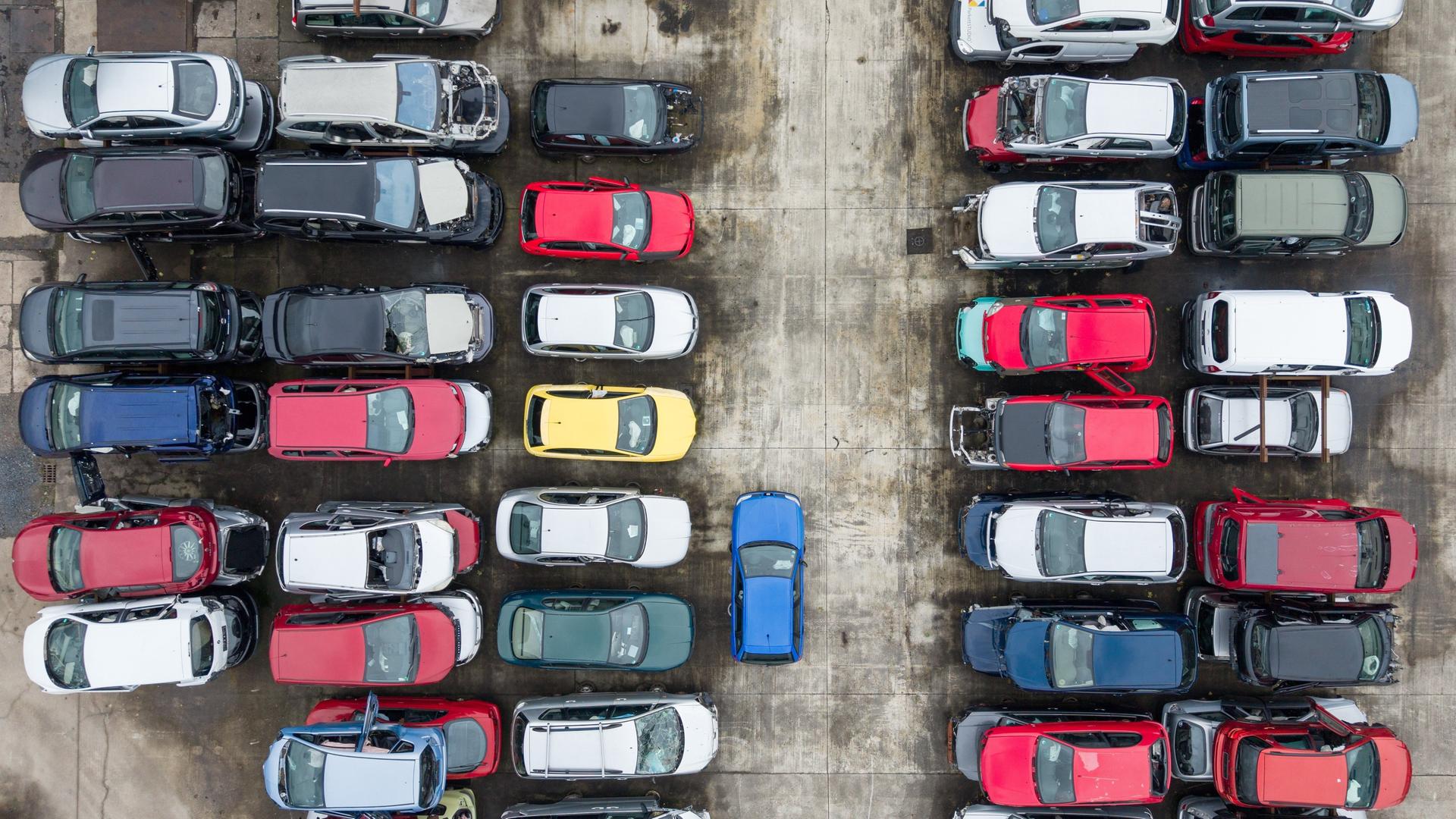 Schrottreife Fahrzeuge stehen übereinandergestapelt auf dem Areal einer Autoverwertung.