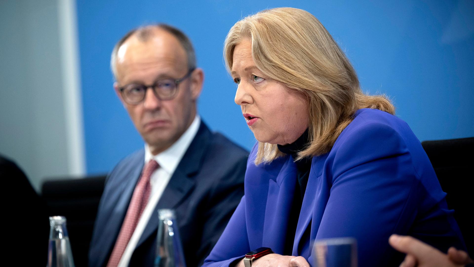 Friedrich Merz und Bärbel Bas sitzen nebeneinander in der Bundesprässekonferenz; Bas spricht ins Mikrofon.
