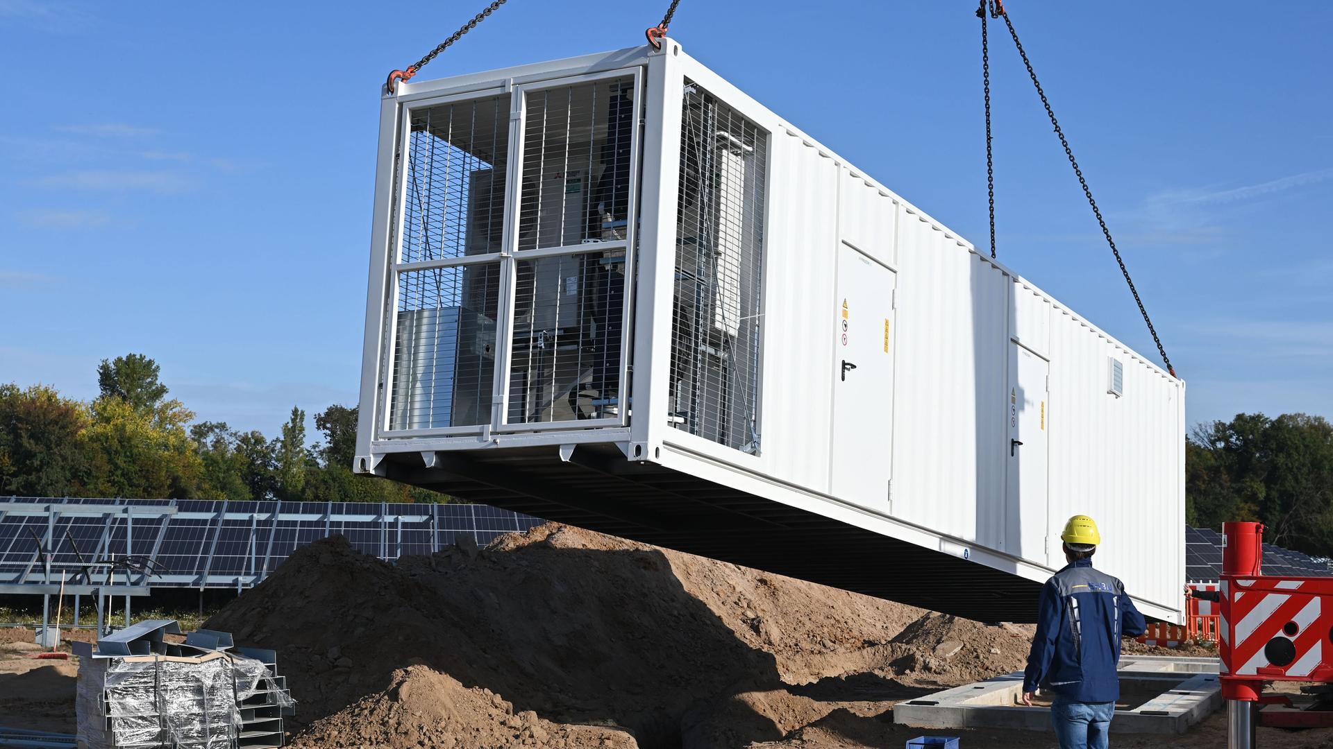 An einem fast fertigen Solarpark des Energieversorgers EnBW wird ein Batteriespeicher angeliefert. 