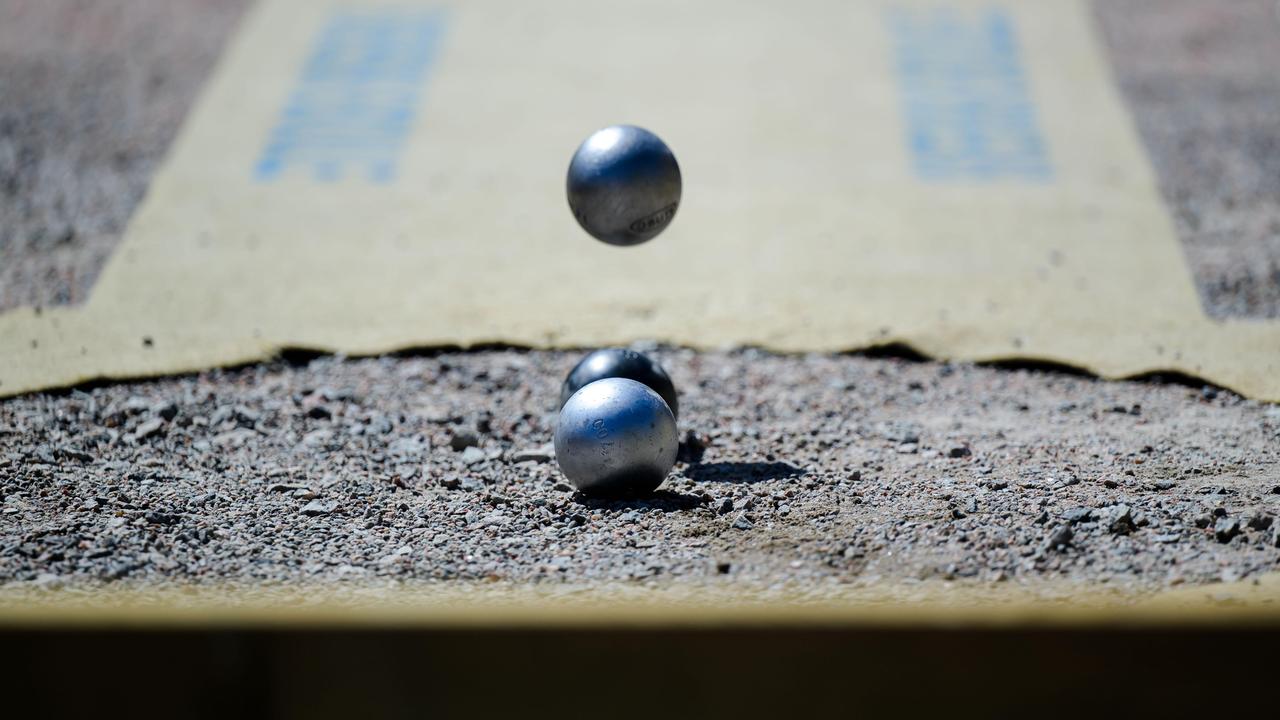 Bei einem Boule-Wettbewerb fließt eine Metallkugel auf zwei liegende Kugeln zu. 