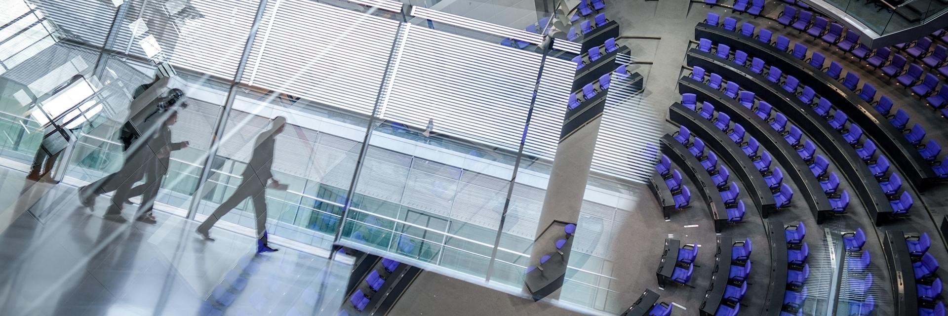 Blick in den Plenarsaal durch eine spiegelnde Fensterscheibe.