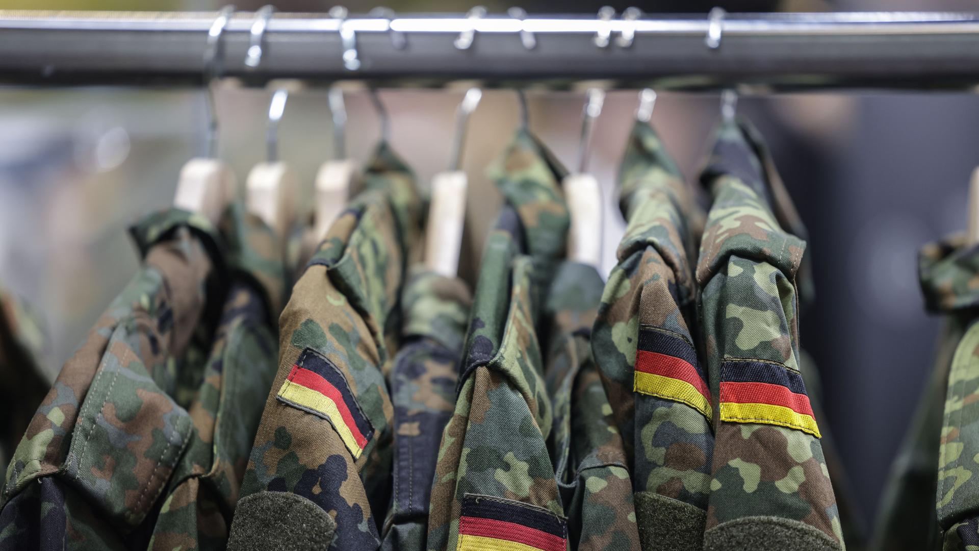 Feldjacken der Bundeswehr hängen auf Kleiderbügeln an einer Stange. 