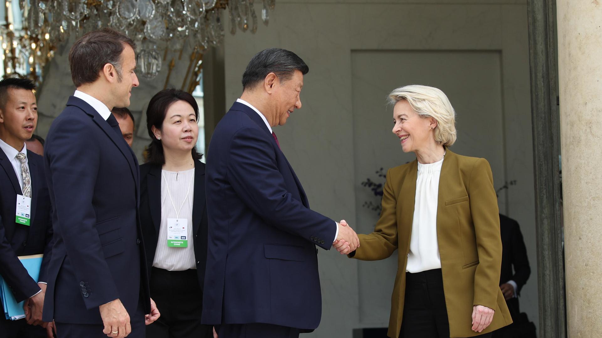 Der chinesische Präsident Xi Jingping und EU-Kommisionspräsidentin Ursula von der Leyen geben sich vor dem Élysée Palast in Paris die Hand. Links von ihnen ist Frankreichs Präsident Emmanuel Macron.