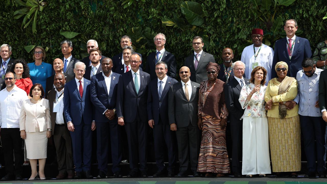 Politiker verschiedener Länder stehen nebeneinander und schauen in die Kamera.
