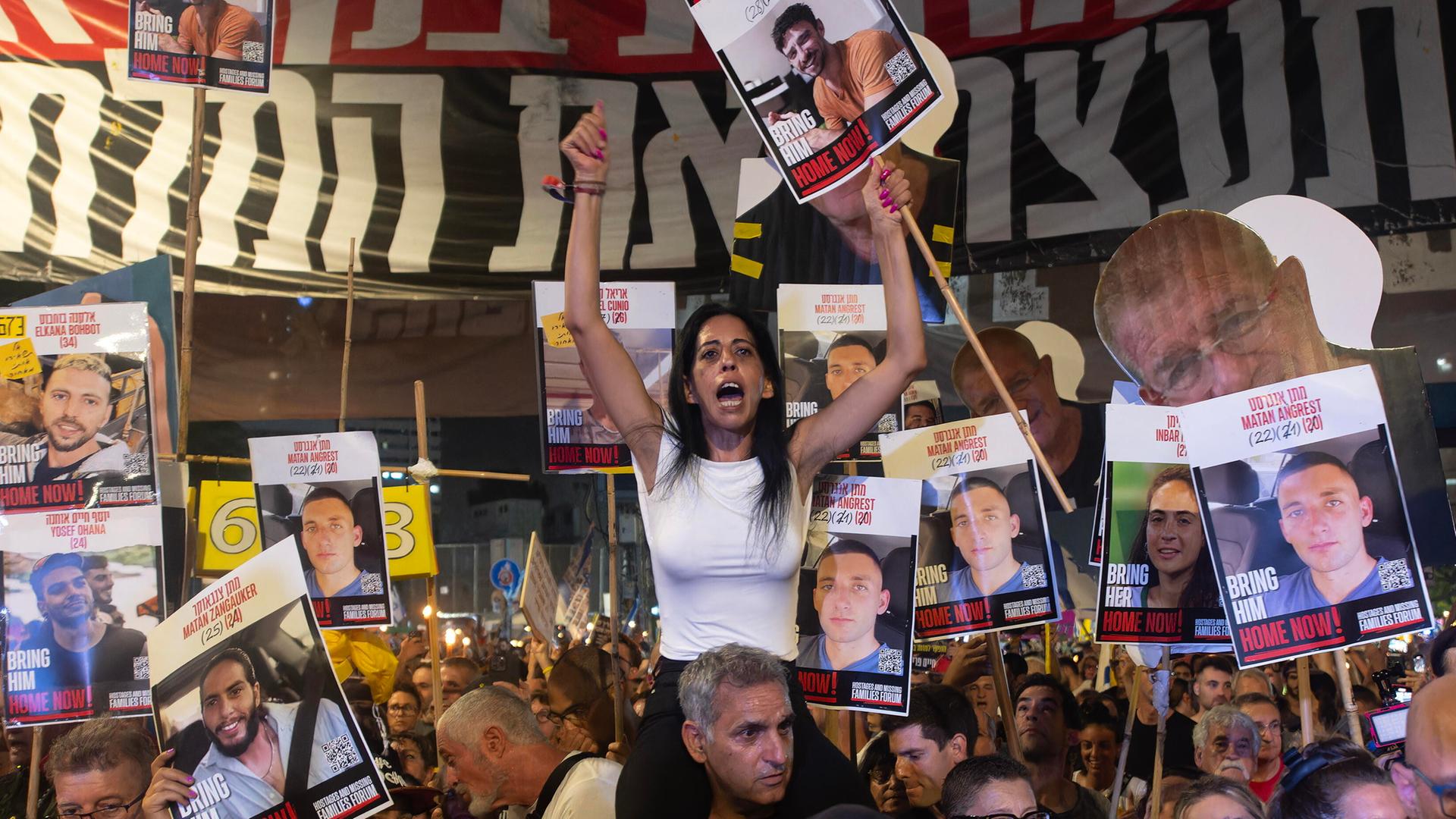 Auf einer Demonstration in Tel Aviv People fordern Protestierende die Freilassung der Hamas-Geiseln und ein Ende des Krieges in Gaza. In der Mitte sitzt eine Frau auf den Schultern eines Mannes, sie trägt ein Plakat mit dem Foto einer Geisel.