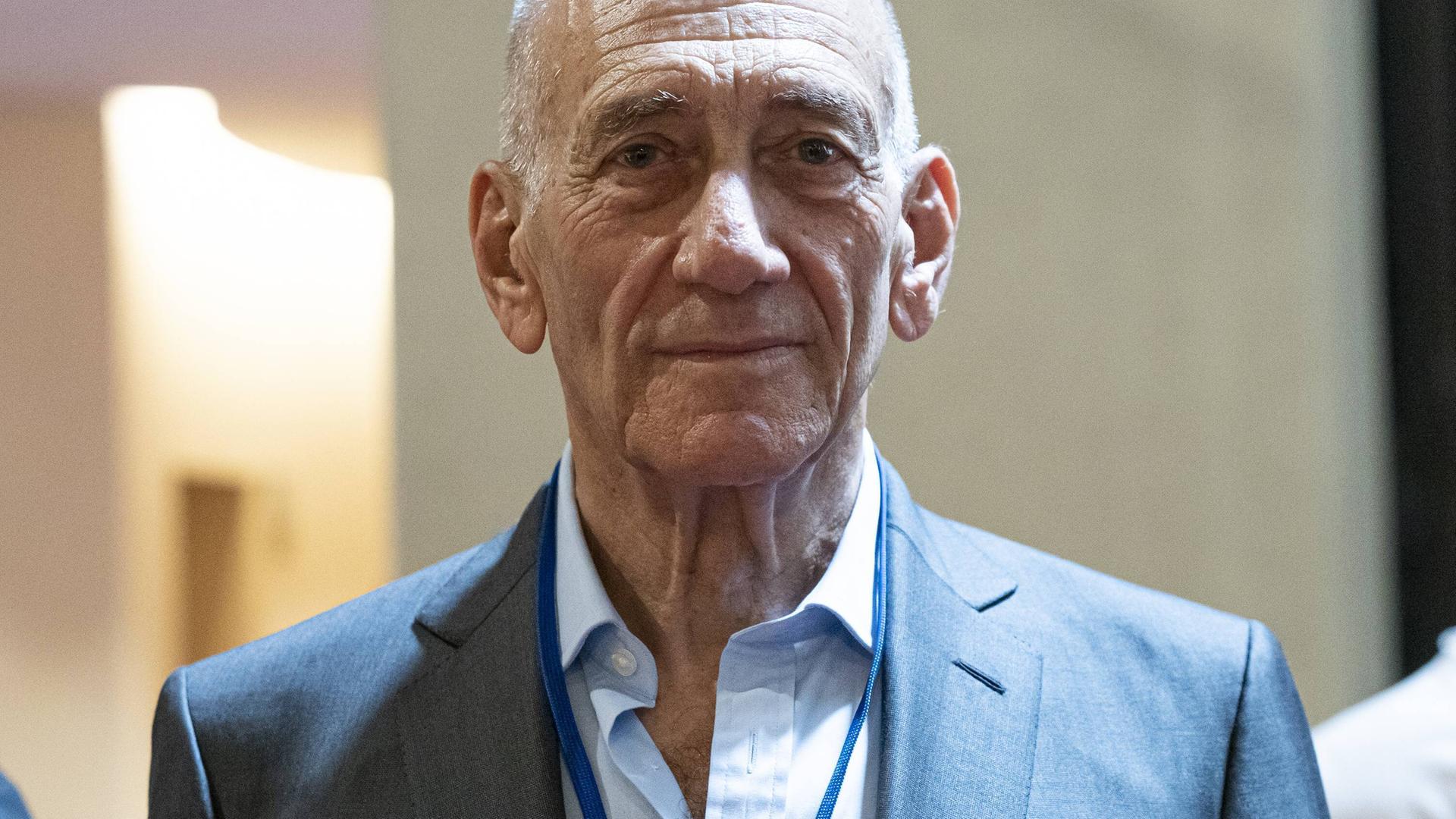Porträt von Ehud Olmert, der einen hellen Anzug trägt und freundlich in die Kamera schaut.