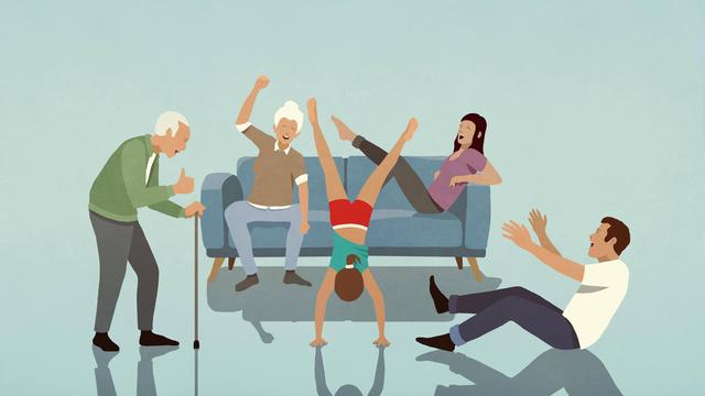 Glückliche Mehrgenerationen-Familie jubelt einem Mädchen zu, das im Wohnzimmer einen Handstand macht.