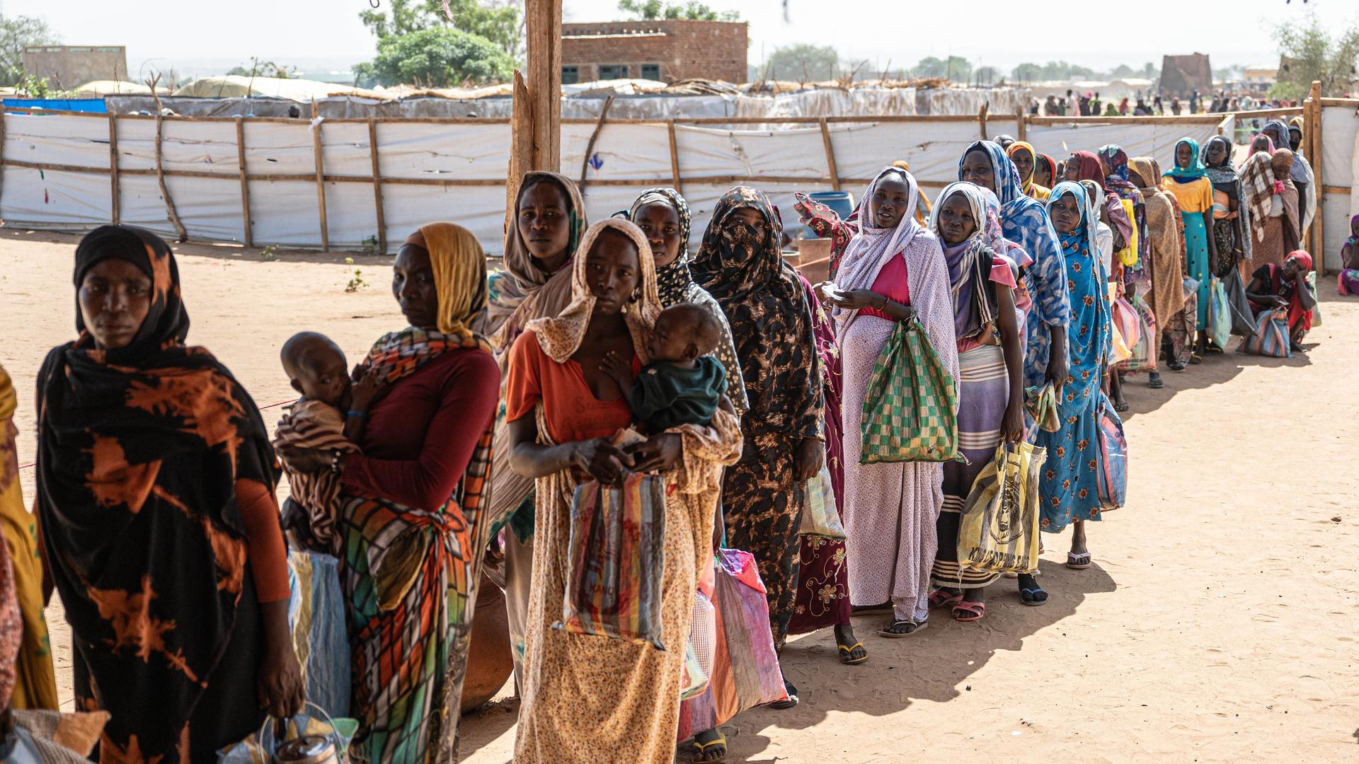 Sudanesische Frauen und Kinder warten in einer Registrierungsstelle in Adre, Tschad, in einer Schlange auf die Verteilung von Hilfsgütern.