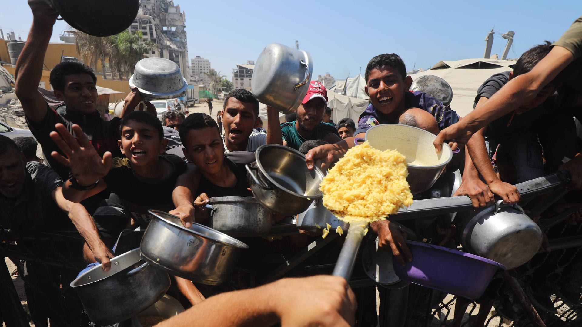 Palästinenser mit leeren Töpfen in der Hand bei einer Essenverteilung in Gaza