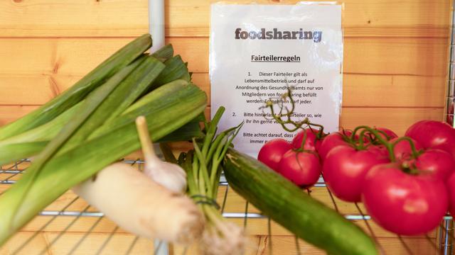 Lauch, eine Gurke und Tomaten liegen in einem Fach, dahinter hängt ein Zettel, auf dem "foodsharing" steht.