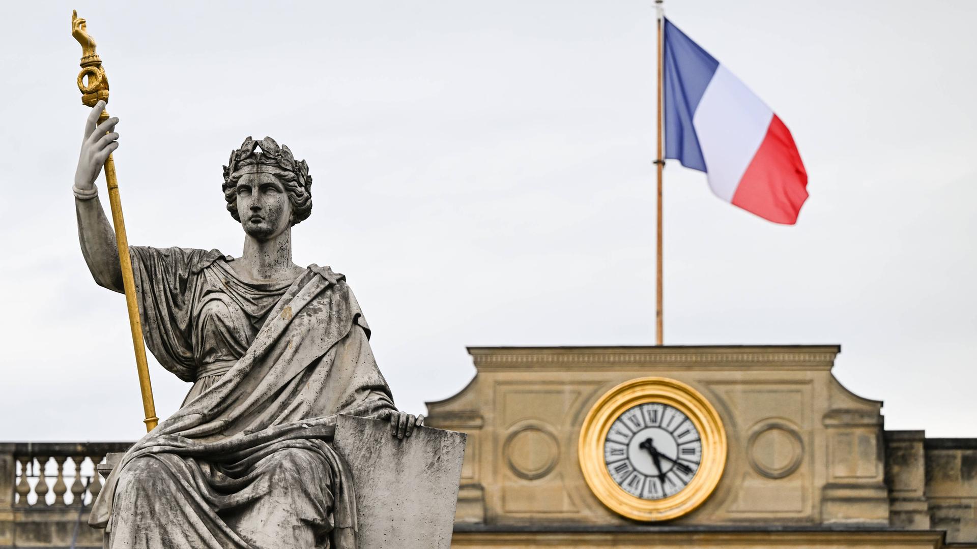 Die Statue der Marianne vor dem Gebäude der Nationalversammlung in Paris, auf dessen Dach die französische Flagge weht 