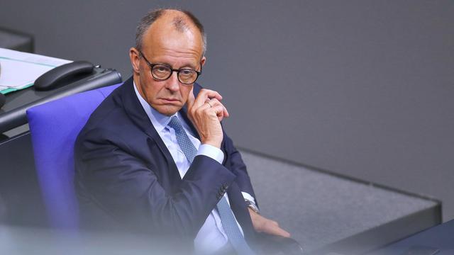 Bundeskanzler Friedrich Merz sitzt während der 25. Bundestagssitzung im Bundestag und fasst sich mit der rechten Hand hinter das linke Ohr.