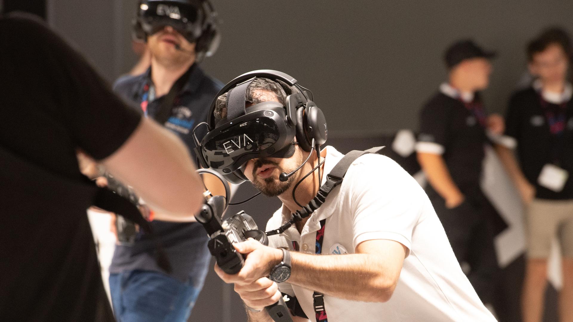 Besucher spielen ein virtuelles Ego-Shooter-Spiel auf der Messe Gamescom in Köln 2023.