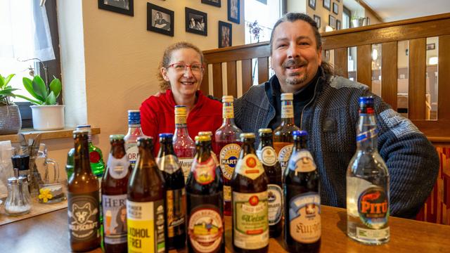 Kerstin Gößl und Vladimir Kloz sitzen hinter zahlreichen Flaschen alkoholfreier Biere und weiterer alkoholfreier Getränke