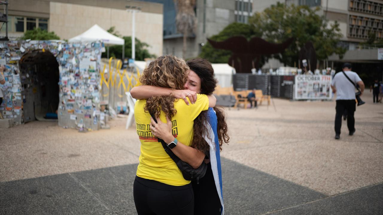 Zwei Frauen umarmen sich auf dem Platz der Geiseln in Tel Aviv. Die eine hat eine israelische Flagge umgebunden, die andere trägt ein gelbes T-Shirt, das die Forderung nach Freilassung der Geiseln symbolisiert.
