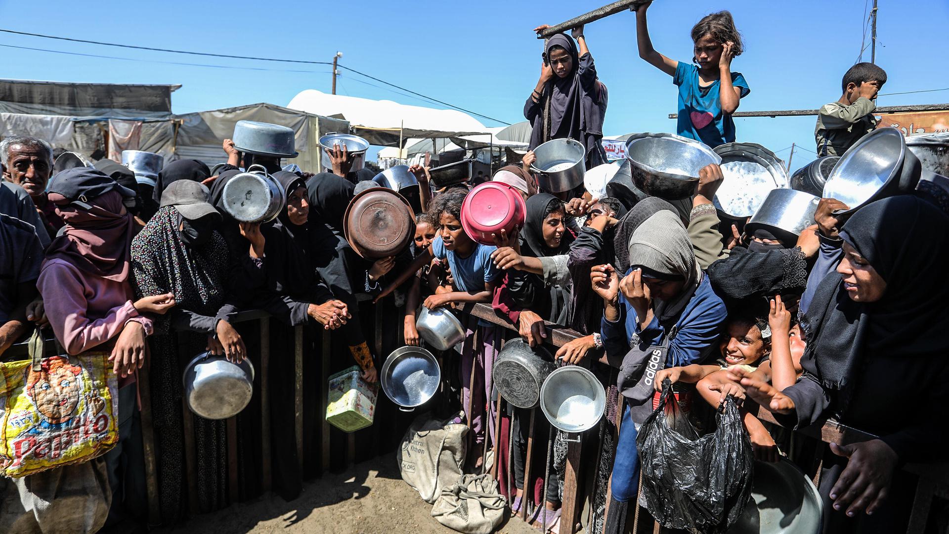 Menschen in Gaza halten leere Schüsseln und Töpfe in der Hand und warten auf die Essensausgabe am 14. September 2025