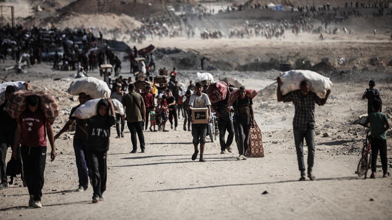 Palästinenser tragen am 5. Oktober 2025 Säcke und Kisten mit Nahrungsmittelhilfe durch den Gazastreifen in Netzarim, wo sich trotz der Gefahren Menschenmengen an einem Verteilungspunkt versammelten.