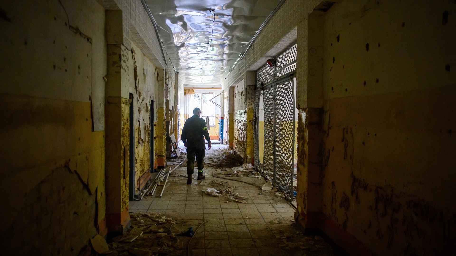 Ein Soldat vom Gefechtsübungszentrum (GÜZ) des Heeres geht auf dem Truppenübungsplatz durch einen Gang eines ehemaligen Wohngebäudes einer Kaserne von der sowjetischen Armee. Von den Wänden blättert die Farbe. Es ist ein verlassener Ort voller Unordnung.