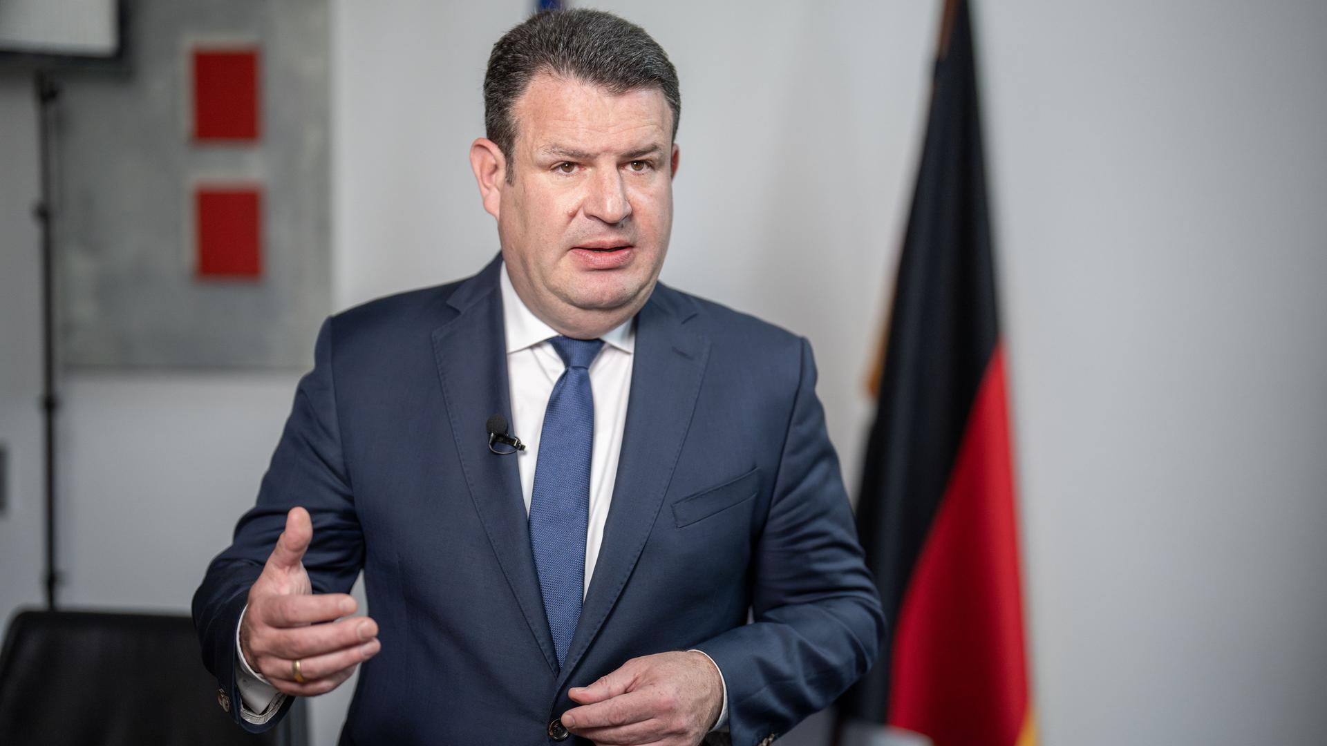 Hubertus Heil gibt ein Interview, im Hintergrund eine Deutschlandflagge.