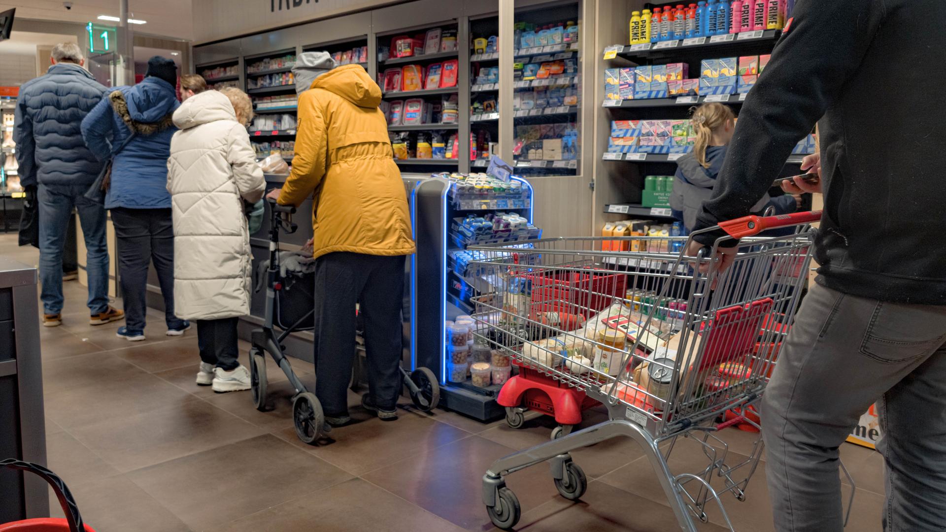 Kunden warten in einem Supermarkt an der Kasse.