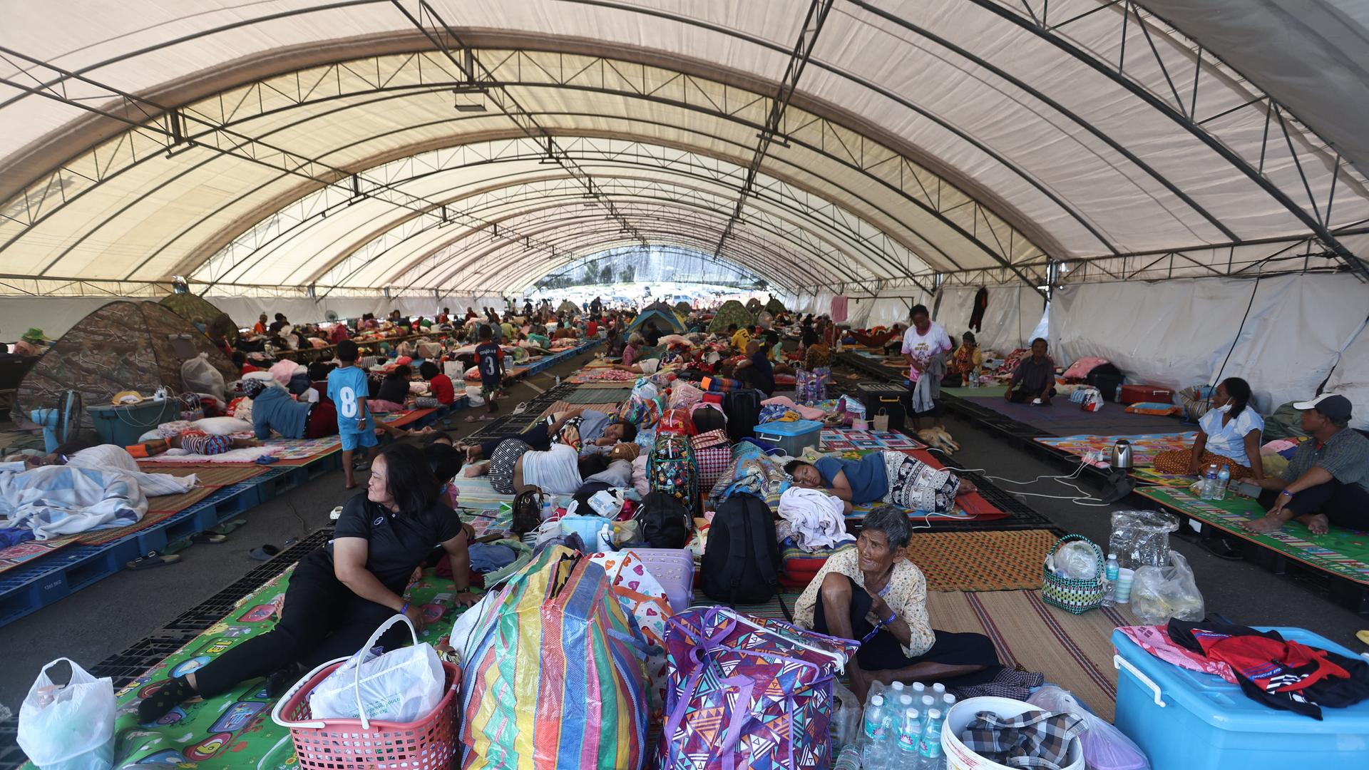 In einem Evakuierungszentrum in der thailändischen Provinz Buriram sitzen und liegen Menschen auf dem Boden und auf einfachen Matten.