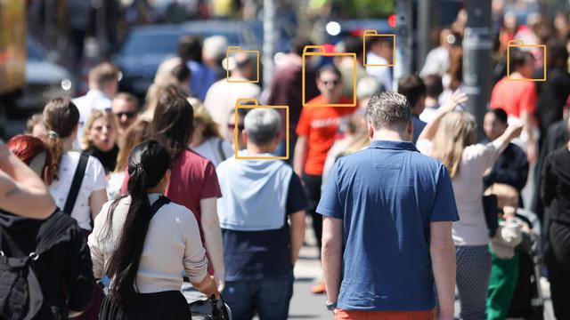 Unscharfes Bild einer Menschenmenge in einer Fußgängerzone. Über manche Gesichter wurden grafische Symbole von Aktenordnern gelegt.