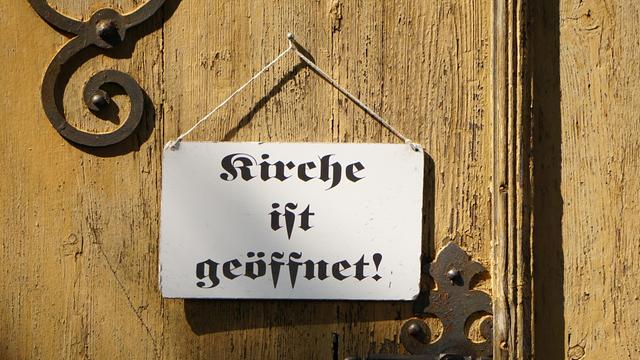 "Kirche ist geöffnet" steht auf dem Schild an einer Kirchentür