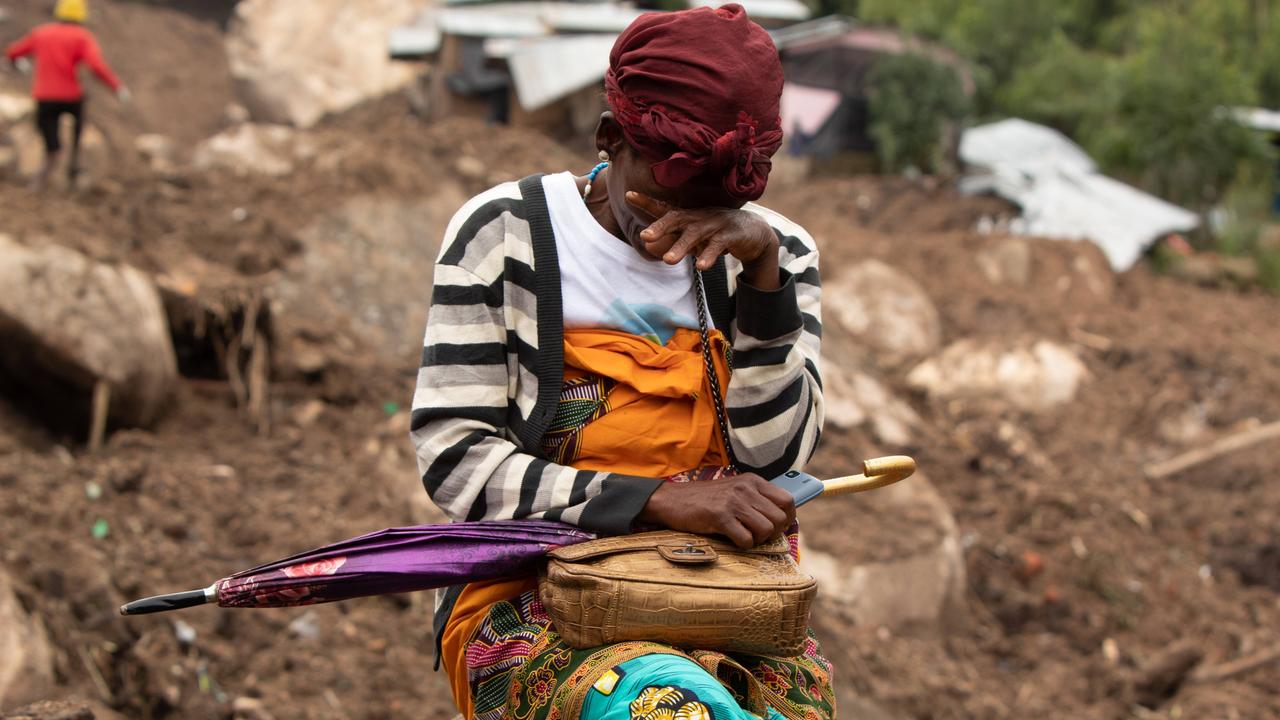 Eine Frau weint in einem vom Zyklon betroffenen Gebiet in Blantyre, Malawi im März 2023. Hinter ihr die zerstörte Stadt, Dächer und Hausteile liegen im Matsch.