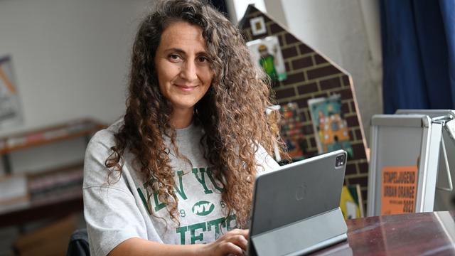 Lale Öztürk, eine Frau mit langen, lockigen Haaren, arbeitet an einem iPad.