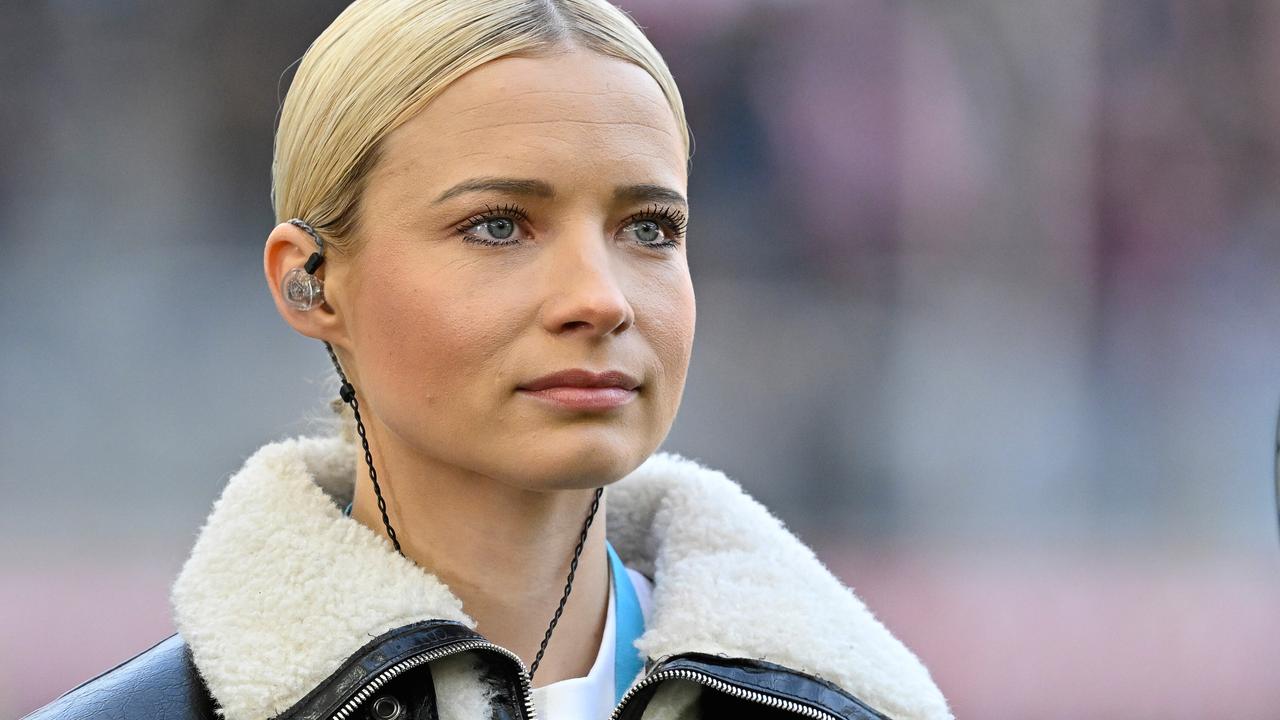 Moderatorin Lena Cassel mit In-Ear.Kopfhörern auf dem Fußballplatz