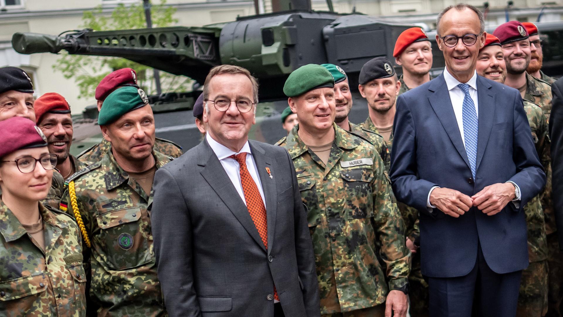 Bundeskanzler Merz (CDU, r) steht mit Verteidigungsminister Pistorius (SPD, M) bei Soldaten der Panzerbrigade 45 der Bundeswehr. Sie ist dauerhaft in Litauen stationiert und soll die Ostflanke der NATO unterstützen