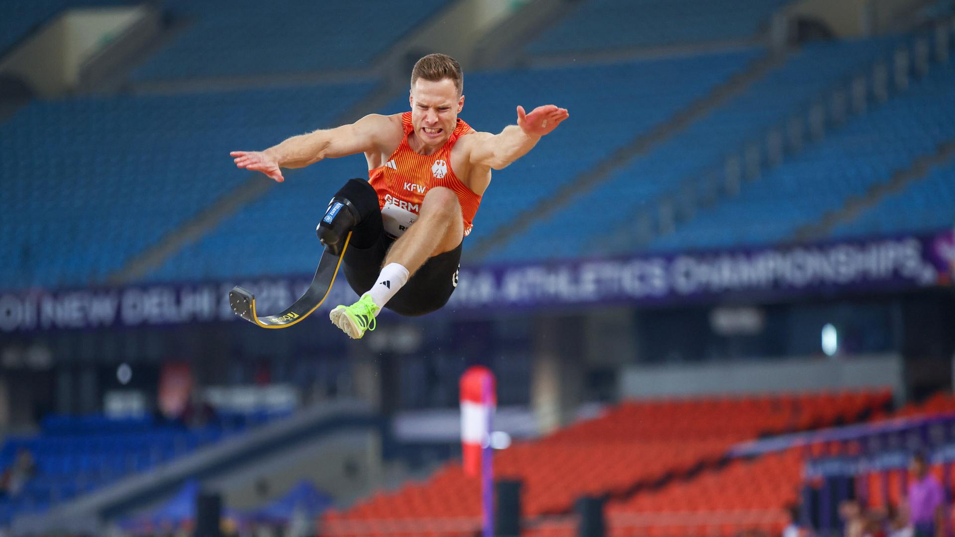 Markus Rehm trägt eine Unterschenkelprothese und springt in einem Stadion durch die Luft