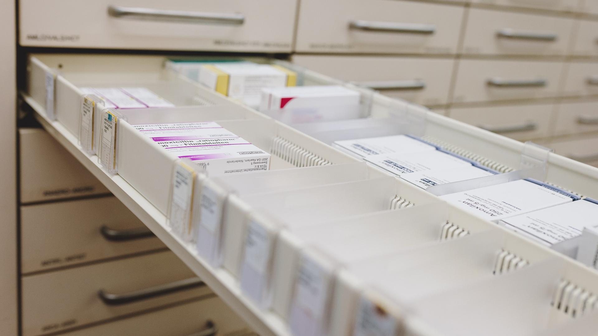 Ein geöffneter Arzneimittelschrank in einer Apotheke zeigt mehrere Packungen Medikamente.