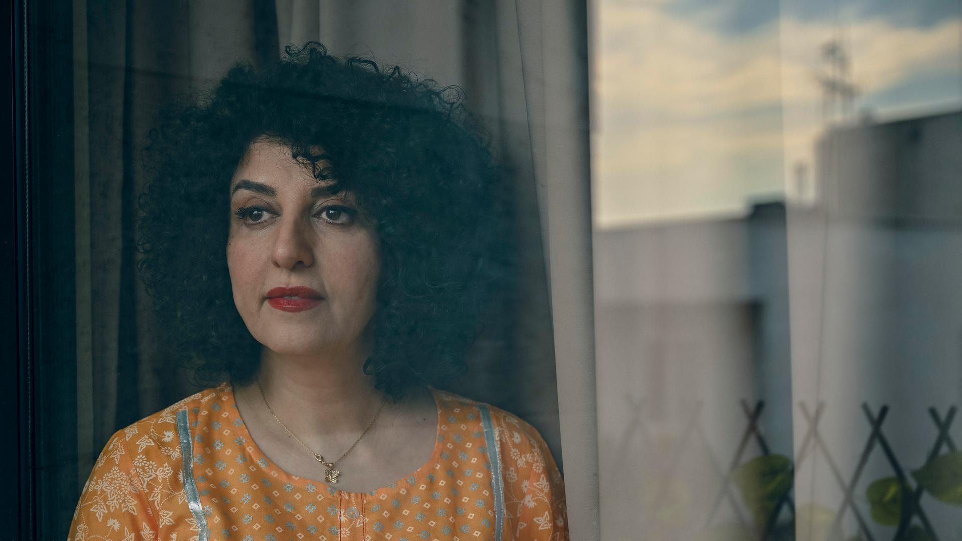 Die Friedensnobelpreisträgerin Narges Mohammadi steht mit gelber Bluse vor einem Fenster.