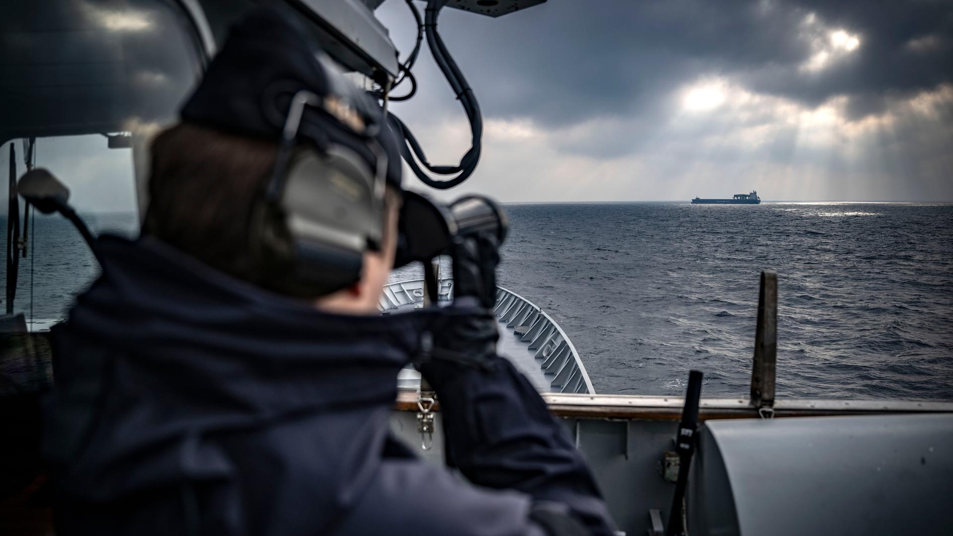 Ein Frachtschiff am Horizont wird vom Brückendeck eines schwedischen Nato-Schiffes aus durch das Fernglas des Ausgucks betrachtet. 
