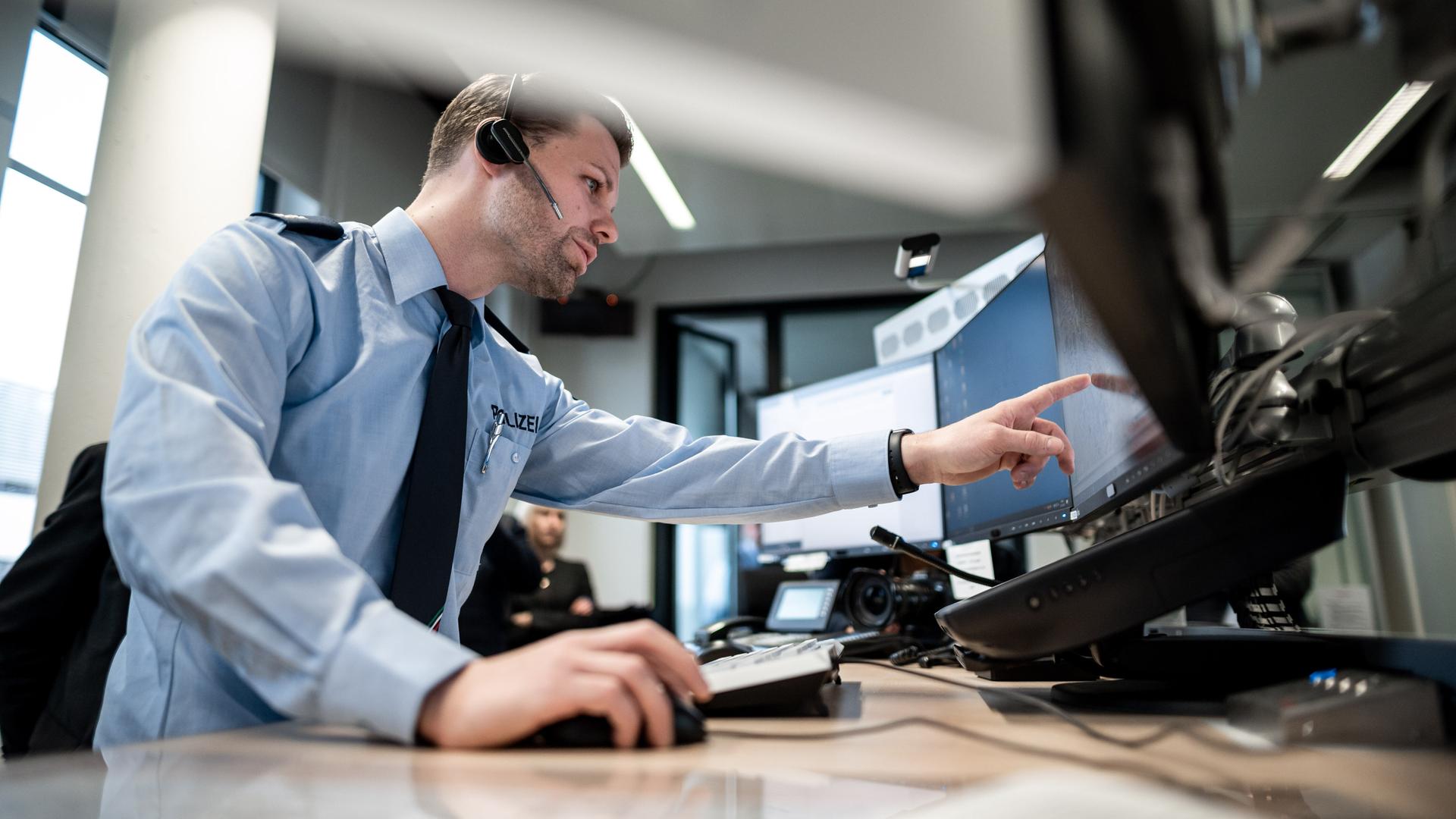 Ein Polizist zeigt auf einen Monitor. Er stellt ein neues GPS-Monitoring bei der Polizei in Mönchengladbach vor. Der Einsatz der Streifenwagen soll damit besser gesteuert werden.