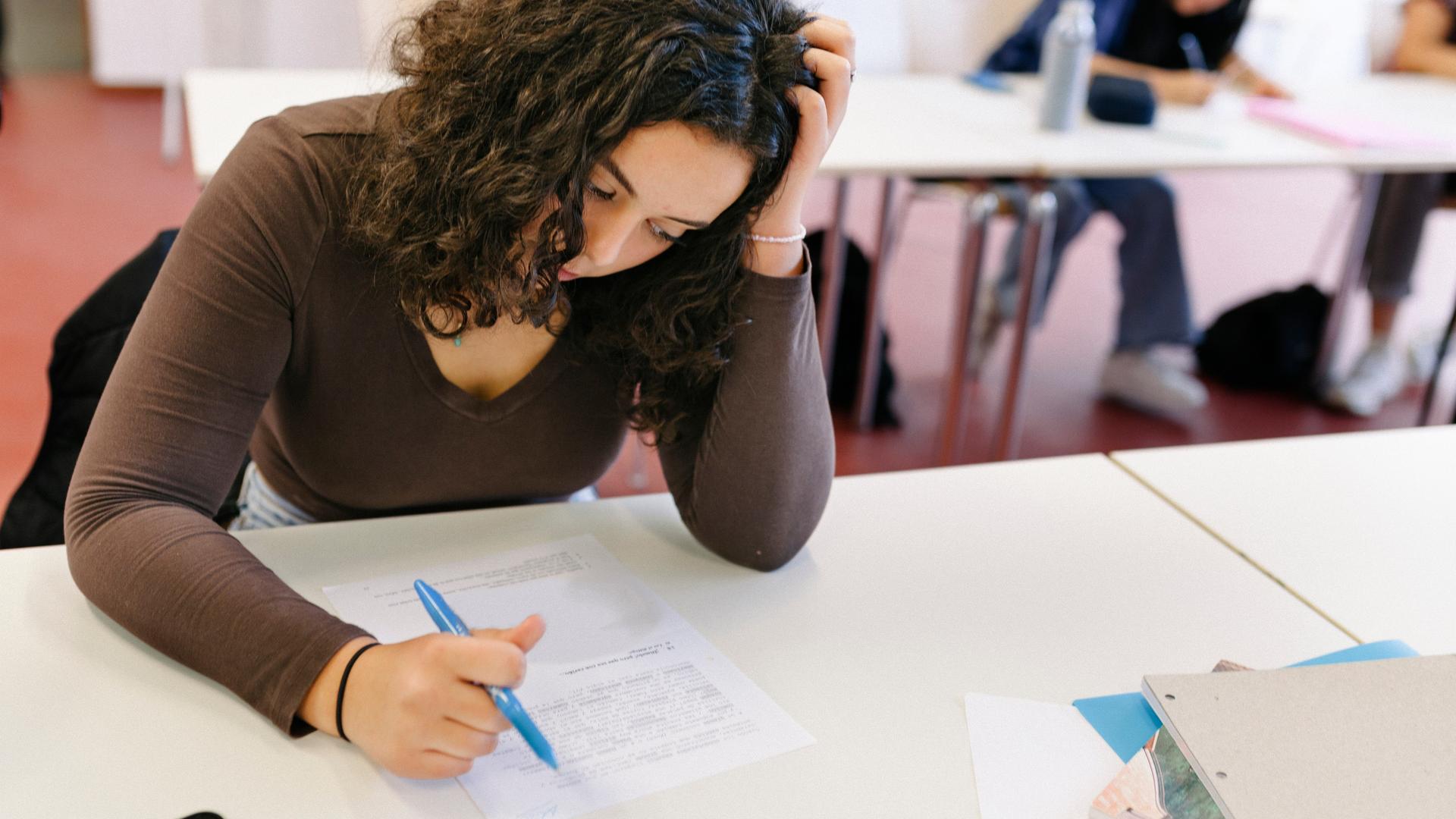 Eine Schülerin ist offensichtlich angestrengt von den Aufgaben, die vor ihr liegen.