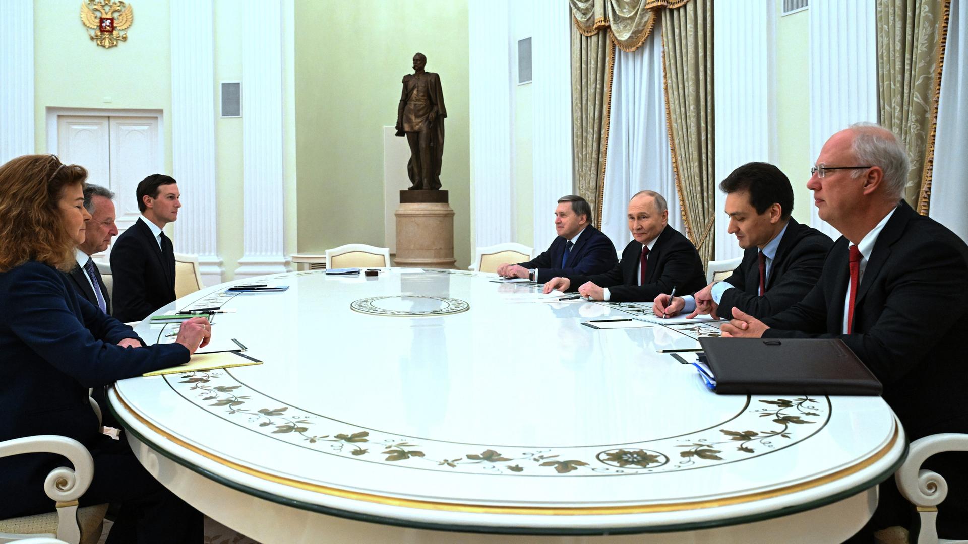 An einem großen weißen Tisch sitzen u.a. Russlands Präsident Wladimir Putin und die US-Sondergesandten Steve Witkoff und Jared Kushner