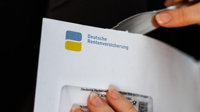 Eine Frau öffnet einen Briefumschlag, auf dem das Logo und der Schriftzug der deutschen Rentenversicherung zu sehen ist.