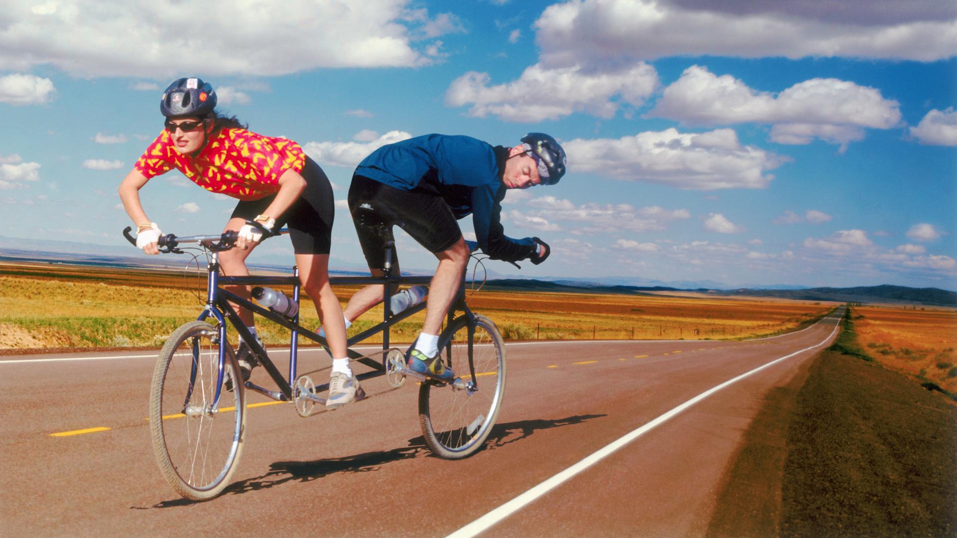 Eine Fahrradfahrerin und ein Fahrradfahrer steuern auf einem Tandem in unterschiedliche Richtungen. (Symbolbild)