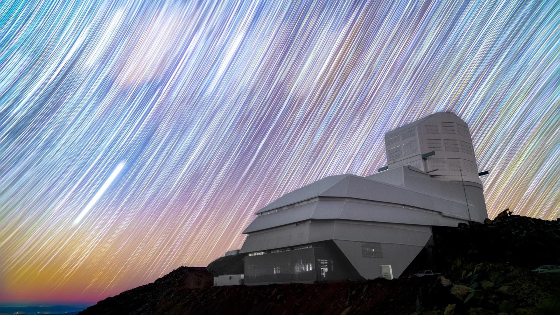 Das Rubin-Observatorium auf dem Cerro Pachón unter dem Sternenhimmel – durch die lange Belichtung hat die Erddrehung die Sterne zu langen Spuren werden lassen. 