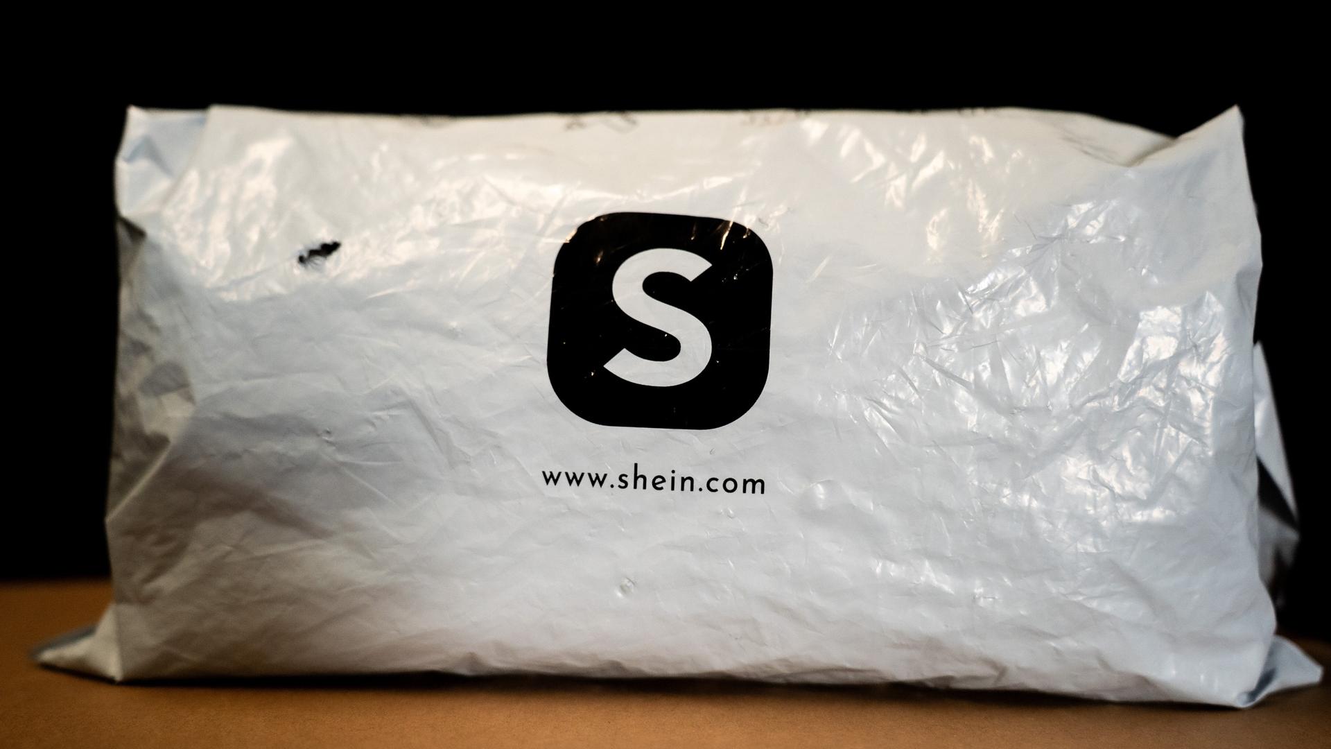 Ein weißes Versandpäckchen aus Kunststoff mit dem schwarzen Logo des Online-Händlers Shein.